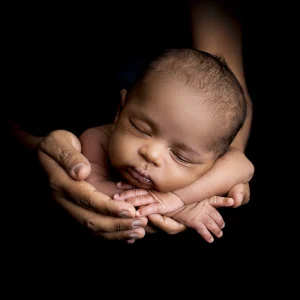 En bild på Lewi där han ligger i pappas händer under sin nyföddfotografering.