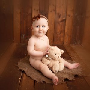 Bebisfotografering på en egentillverkad fotobakgrund av gamla, bruna, träplankor.