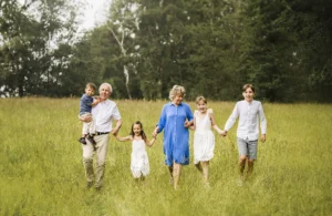 Familjefotografering med farmor och farfar tillsammans med barnbarnen på en sommaräng.