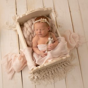 Nyfödd bebis som sover i en docksäng med liten kanin.