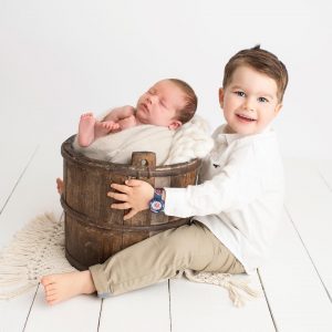 Glad storebror inne på syskonfotografering med sin nyfödda lillebror.